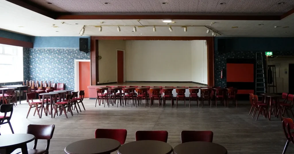 Empty concert room at a working men's club in Knottingley, with bare stage, tables and chairs